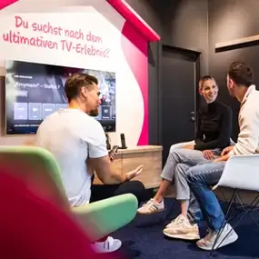 Männer und Frau sitzen im Wohnzimmer, Smart-TV Beratung für TV-Erlebnis