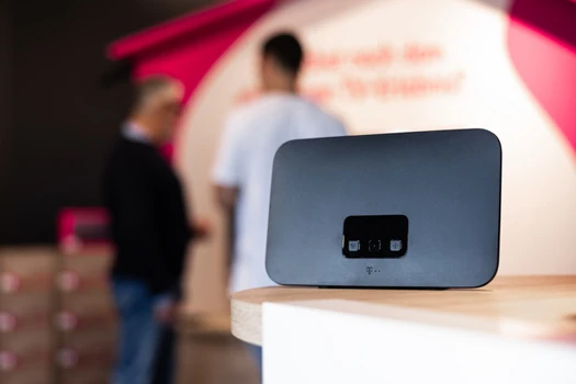 WLAN-Router auf Holztisch, unscharfe Personen im Hintergrund im Laden