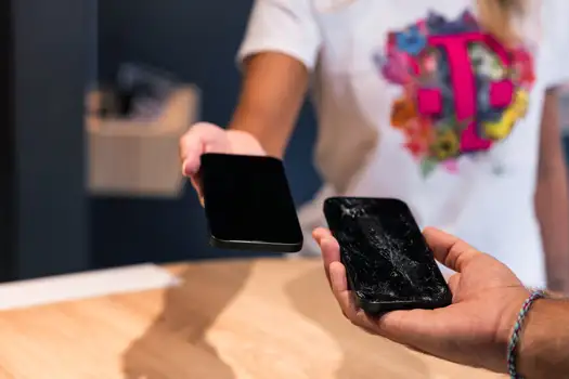 Übergabe eines Smartphone-Displays zur Handyreparatur, kaputtes Handy in Hand